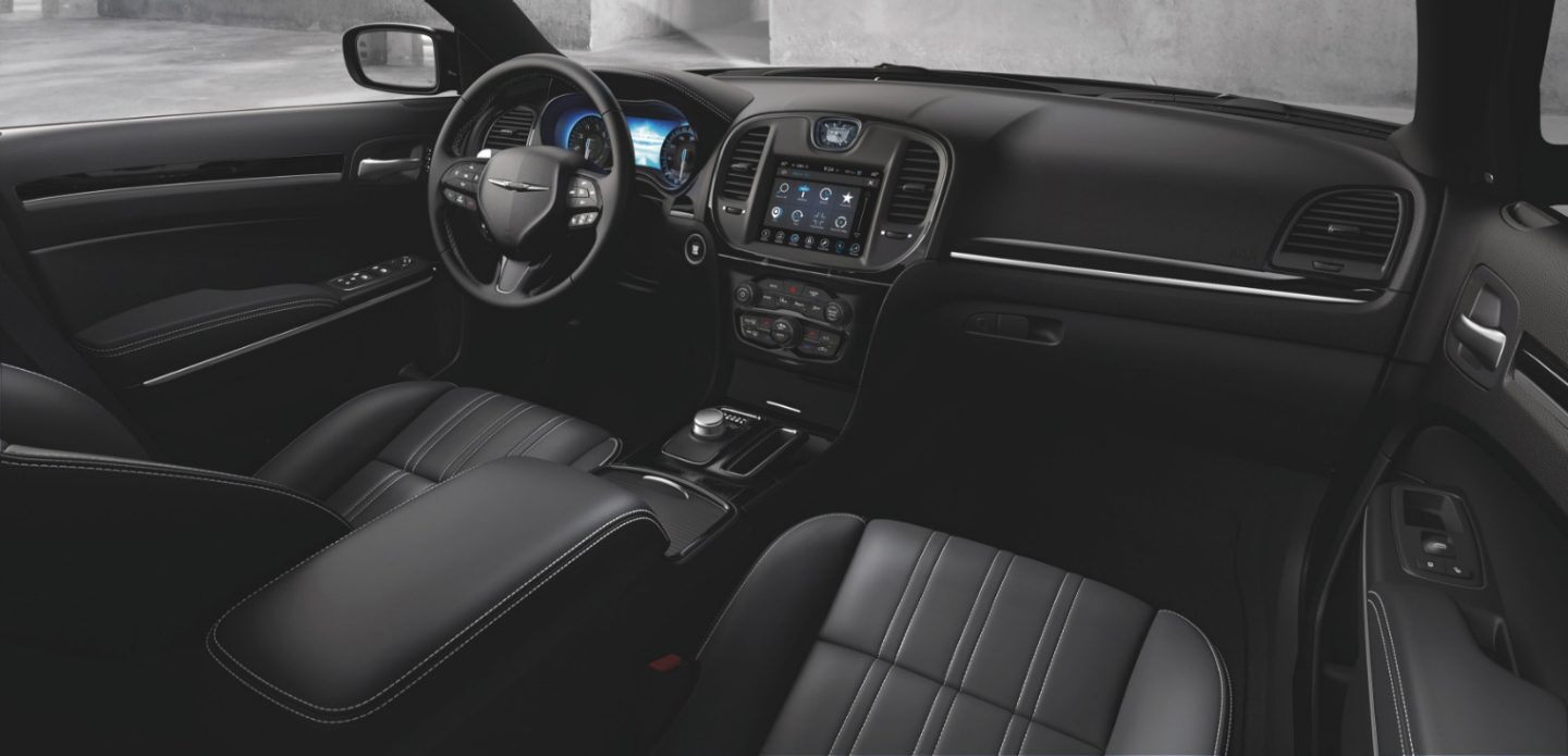 Se muestra el interior del Chrysler 300 2023 con enfoque en los asientos del conductor y el copiloto, el volante, la pantalla táctil y el tablero.