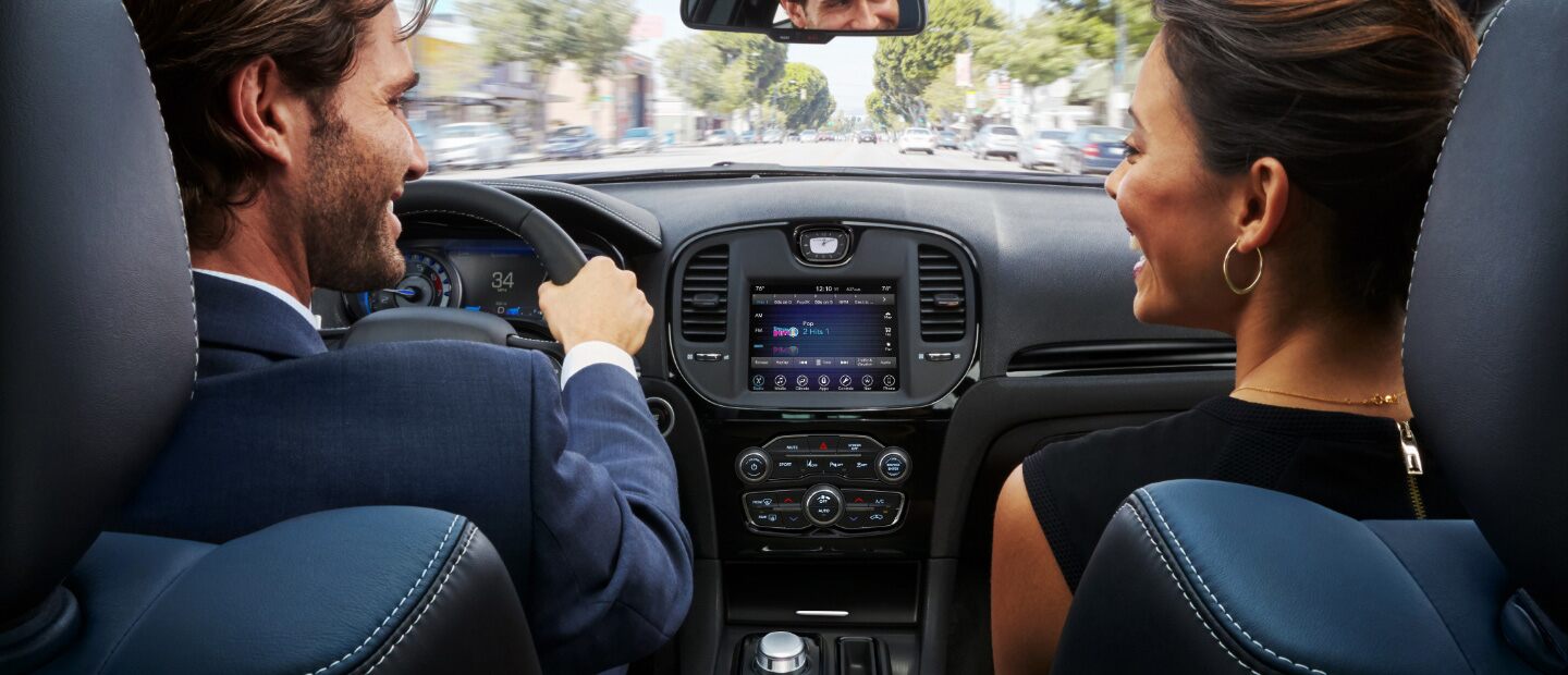 El interior del Chrysler 300 2023 con un conductor y un copiloto conversando en los asientos delanteros.
