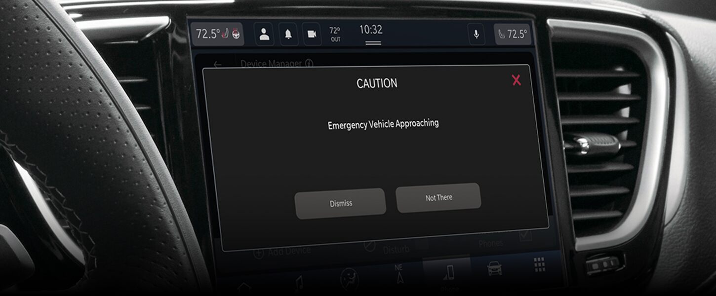Pantalla táctil Uconnect en la Chrysler Pacifica 2024, que muestra la alerta de aproximación de vehículo de emergencia.