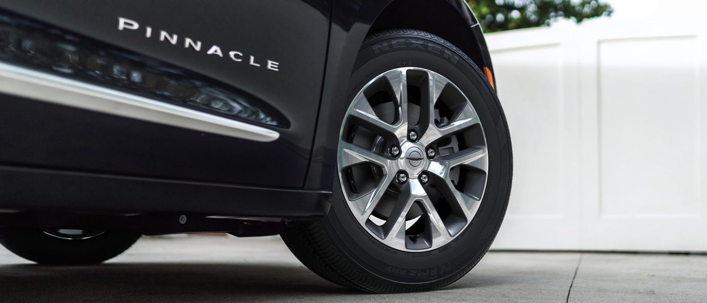 Se muestran una rueda y un neumático de una Chrysler Pacifica Pinnacle Plug-in Hybrid 2025 negra.