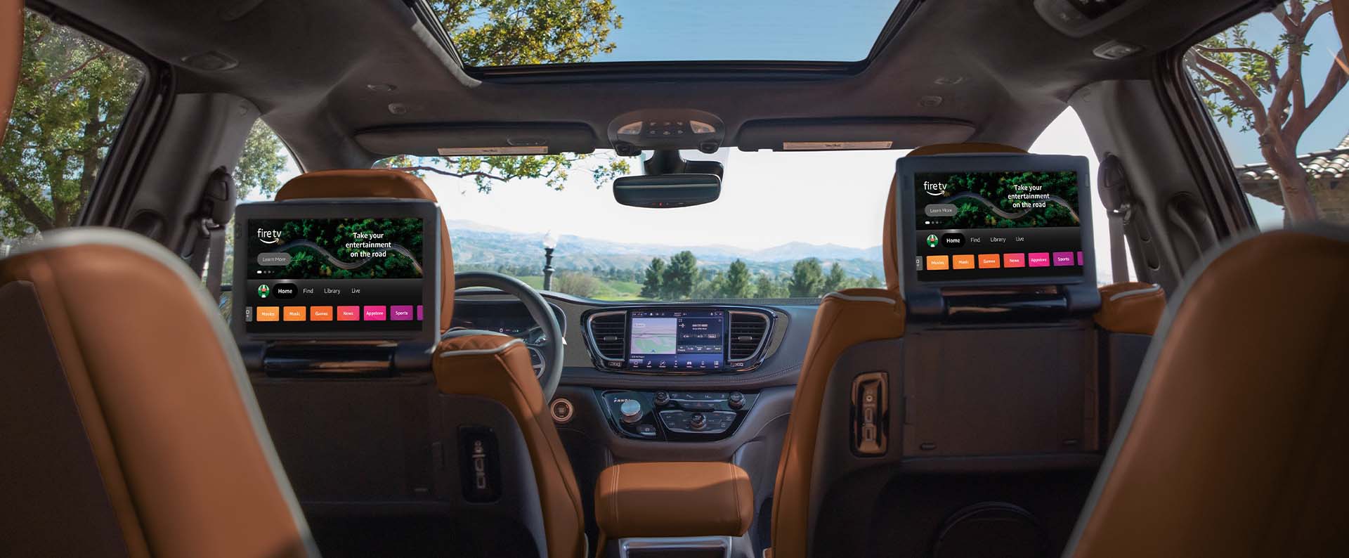 El interior de la Chrysler Pacifica Pinnacle 2025 desde la perspectiva de la tercera fila hacia adelante, con el foco puesto en las dos pantallas táctiles montadas en los respaldos de los asientos delanteros para los pasajeros de la segunda fila, en las que se exhibe Amazon FireTV.