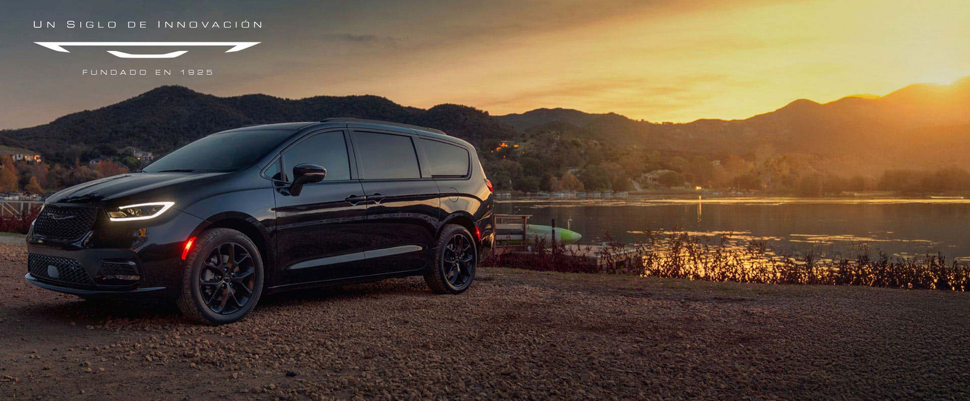Una Chrysler Pacifica Limited 2025 negra estacionada al lado de un lago, al atardecer. Evento de ventas Precios de empleado. Un siglo de innovación.