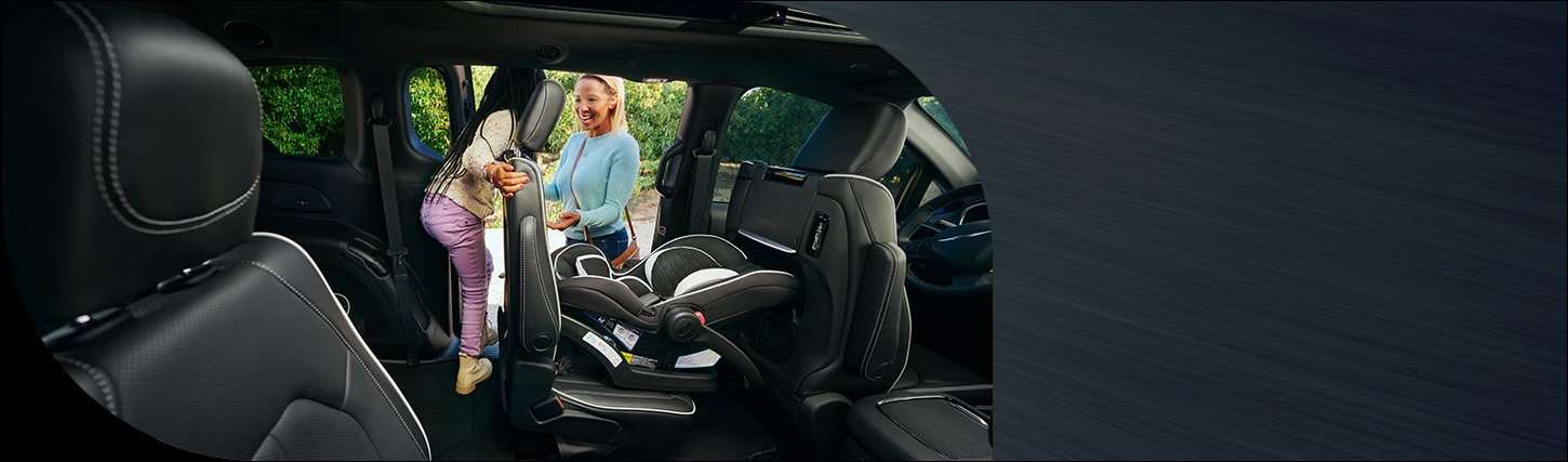 El asiento de la segunda fila del lado del conductor con un asiento infantil colocado en la Chrysler Pacifica Limited 2026 El asiento se inclina hacia adelante para que un niño pueda salir de la tercera fila por la puerta corrediza.
