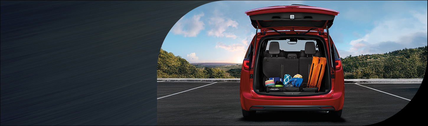 La parte trasera de una Chrysler Pacifica Limited 2026 de color rojo con la puerta trasera levadiza abierta, dejando al descubierto el espacio de carga detrás de los asientos de la tercera fila.
