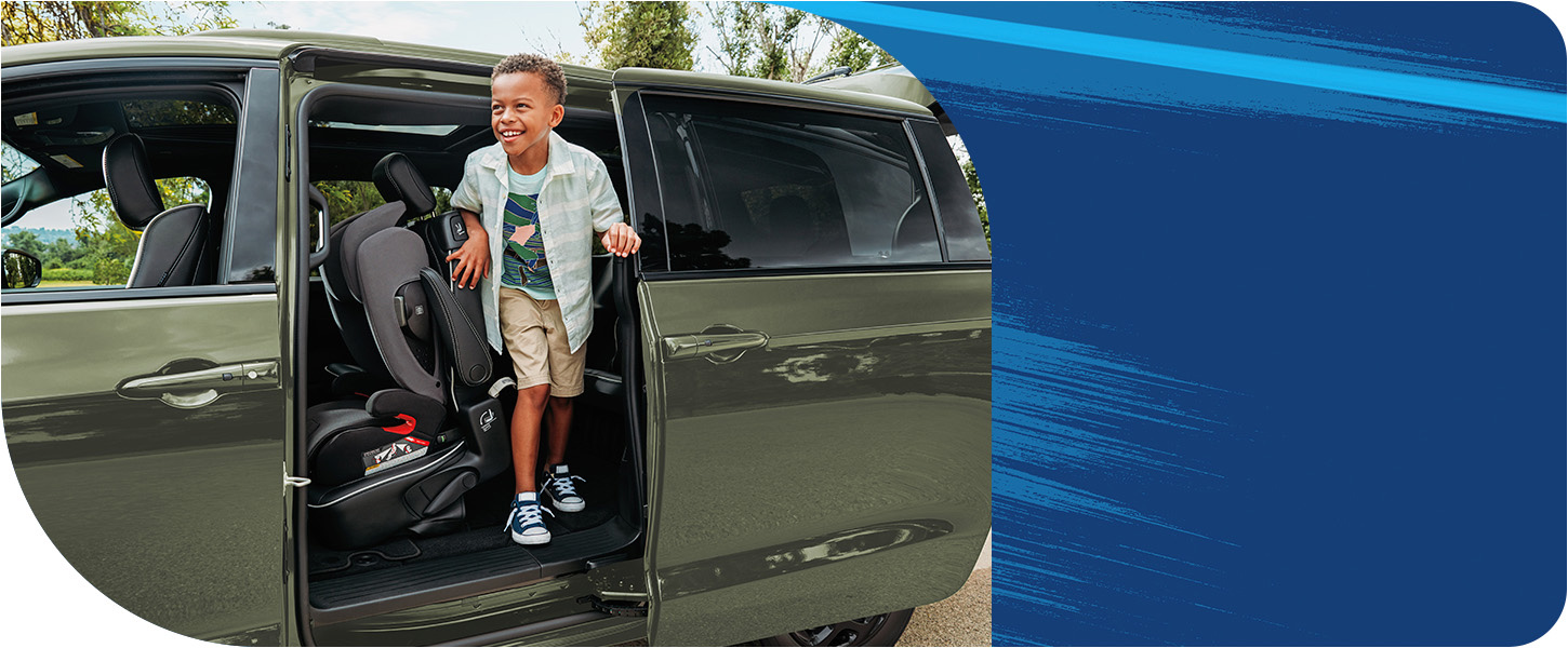 Se muestra el asiento de la segunda fila inclinado hacia adelante con un asiento infantil orientado hacia atrás acoplado, mientras un niño sale de la tercera fila por la puerta lateral del lado del conductor de una Chrysler Pacifica Plug-In Hybrid Select 2026 con el paquete de apariencia Premium S.