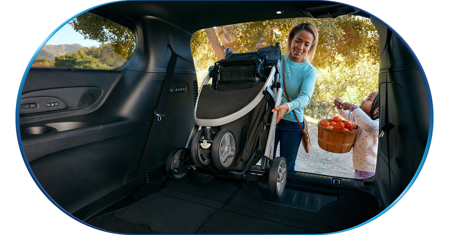 Una mujer saca un cochecito plegado de la zona de carga de una Chrysler Pacifica Hybrid 2026.