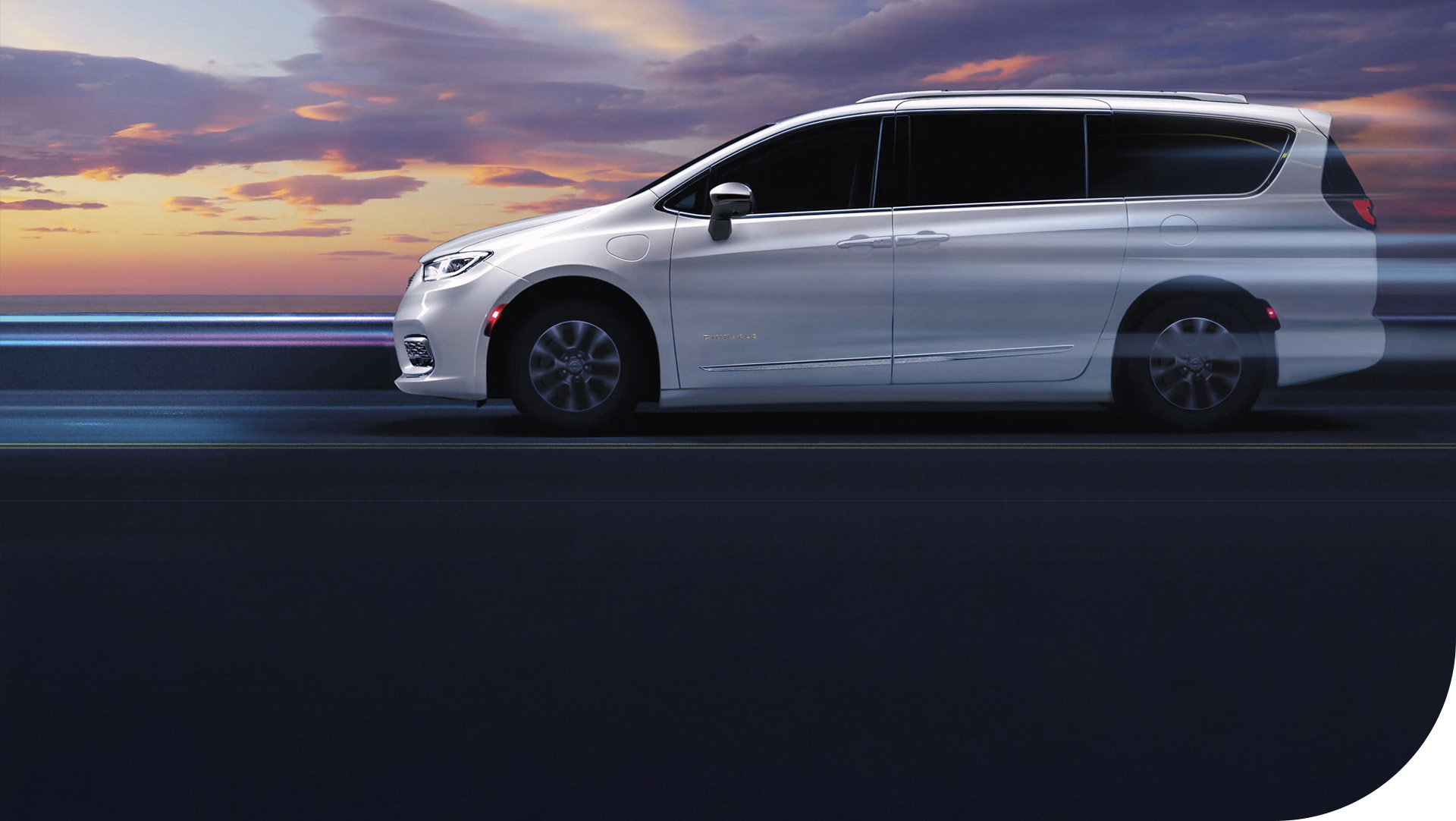 Perfil del lado del conductor de una Chrysler Pacifica Plug-in Hybrid Pinnacle 2026 de color blanco con las ruedas difuminadas para indicar que el vehículo está en movimiento.