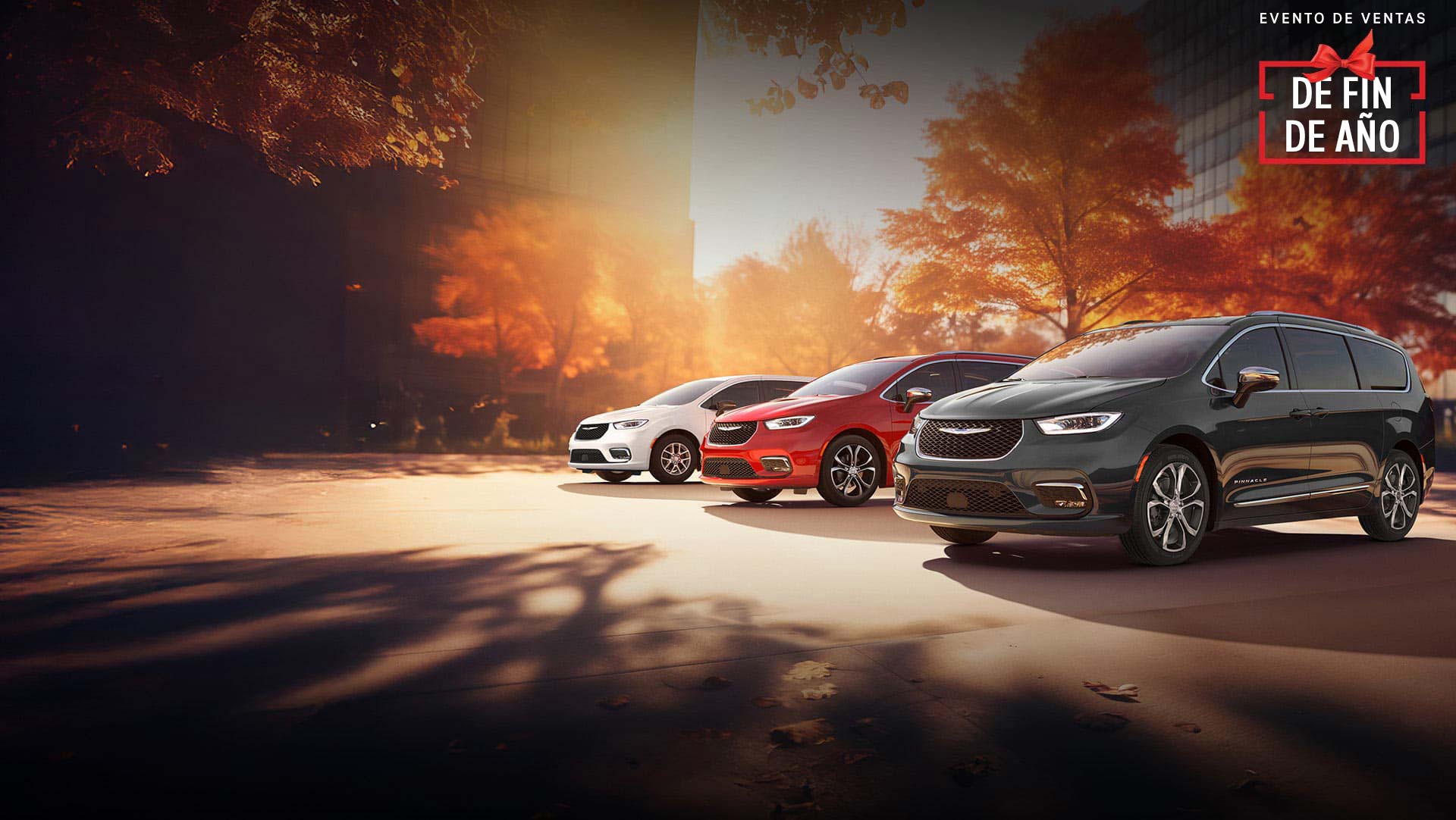 Tres modelos de la minivan Chrysler 2026 estacionados en una playa junto al mar. De izquierda a derecha: Chrysler Voyager blanca, Pacifica Pinnacle Plug-in Hybrid azul y Pacifica Pinnacle roja. Evento de ventas Fin de año.