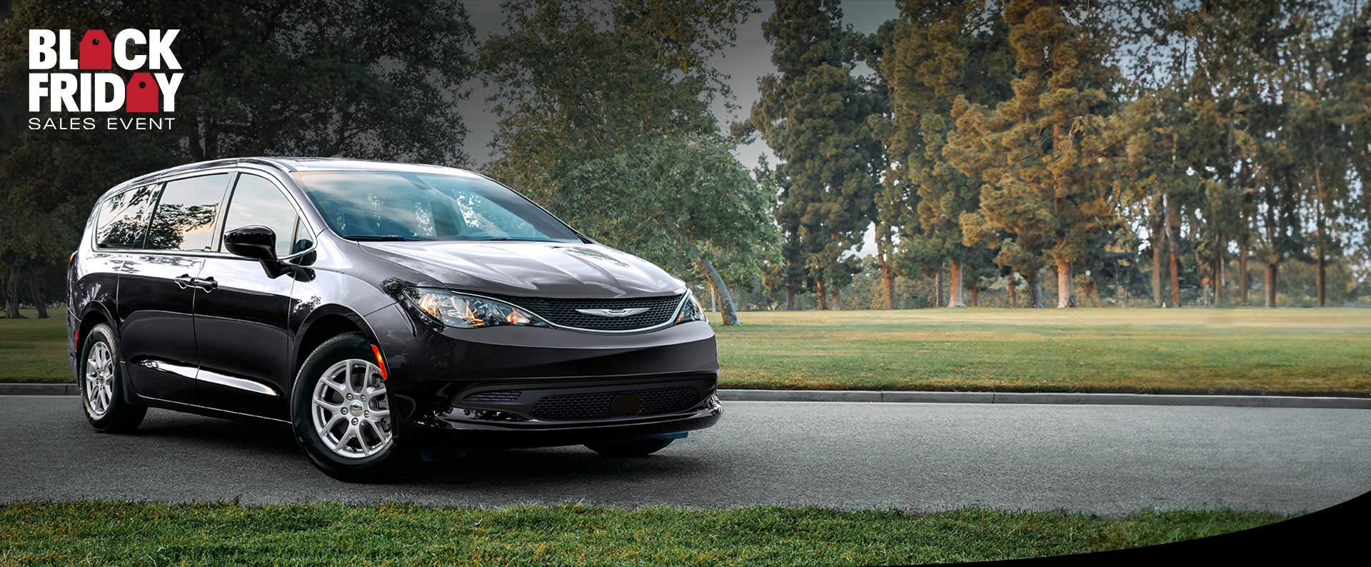 Vista frontal del lado del pasajero del Chrysler Voyager LX 2025 en el estacionamiento de un parque. Evento de ventas Black Friday.