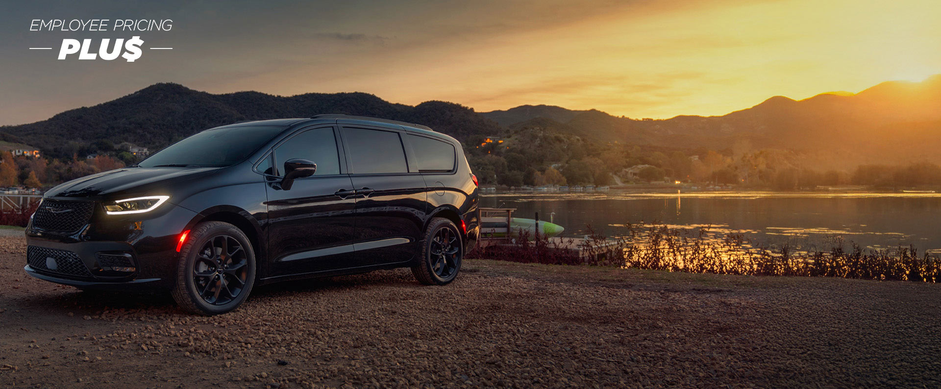Una Chrysler Pacifica Limited 2025 negra estacionada al lado de un lago, al atardecer. Evento de ventas Precios de empleado.