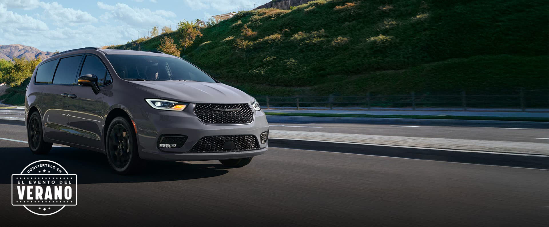 Una Chrysler Pacifica Limited 2025 gris claro circulando por una carretera en las montañas. Conviértelo en el evento de ventas del verano​​​​​​​.