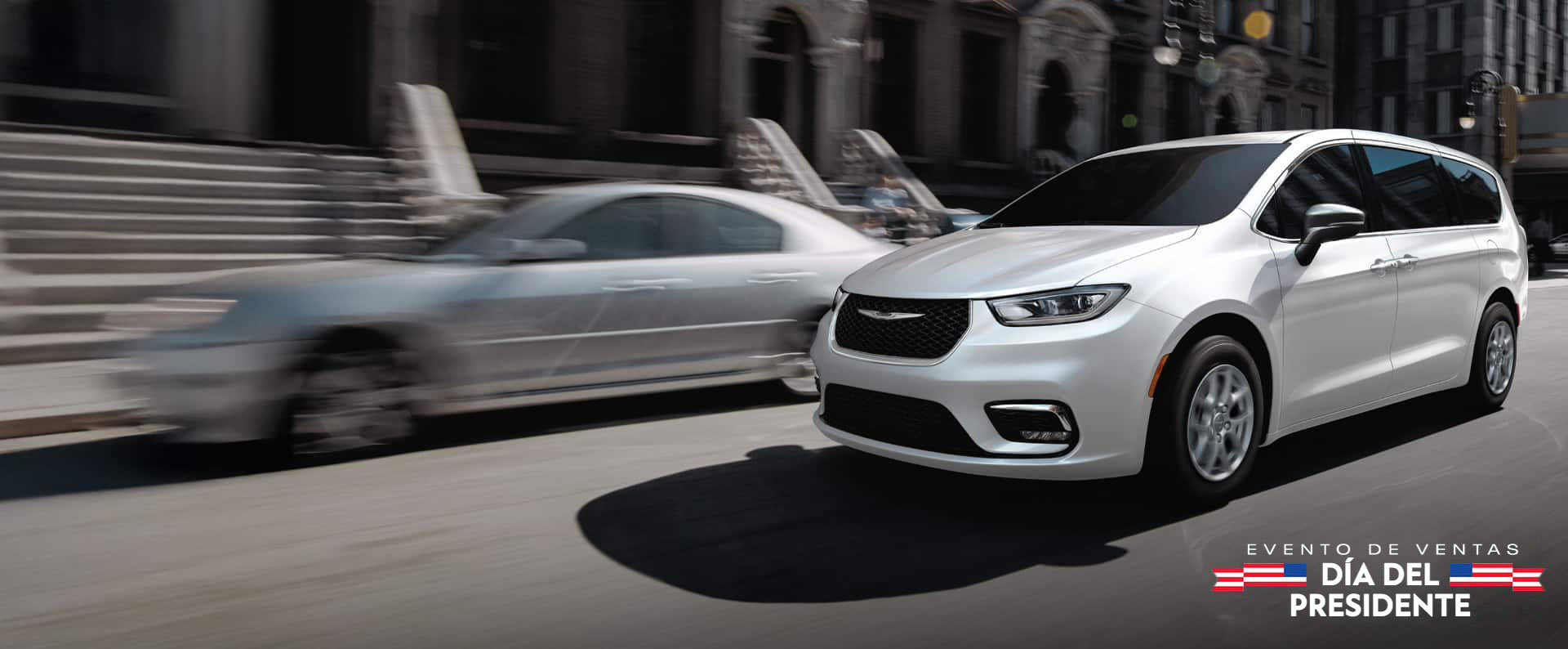 Una Chrysler Pacifica Select 2026 blanca circulando por la calle de una ciudad. Evento de ventas Día del Presidente.