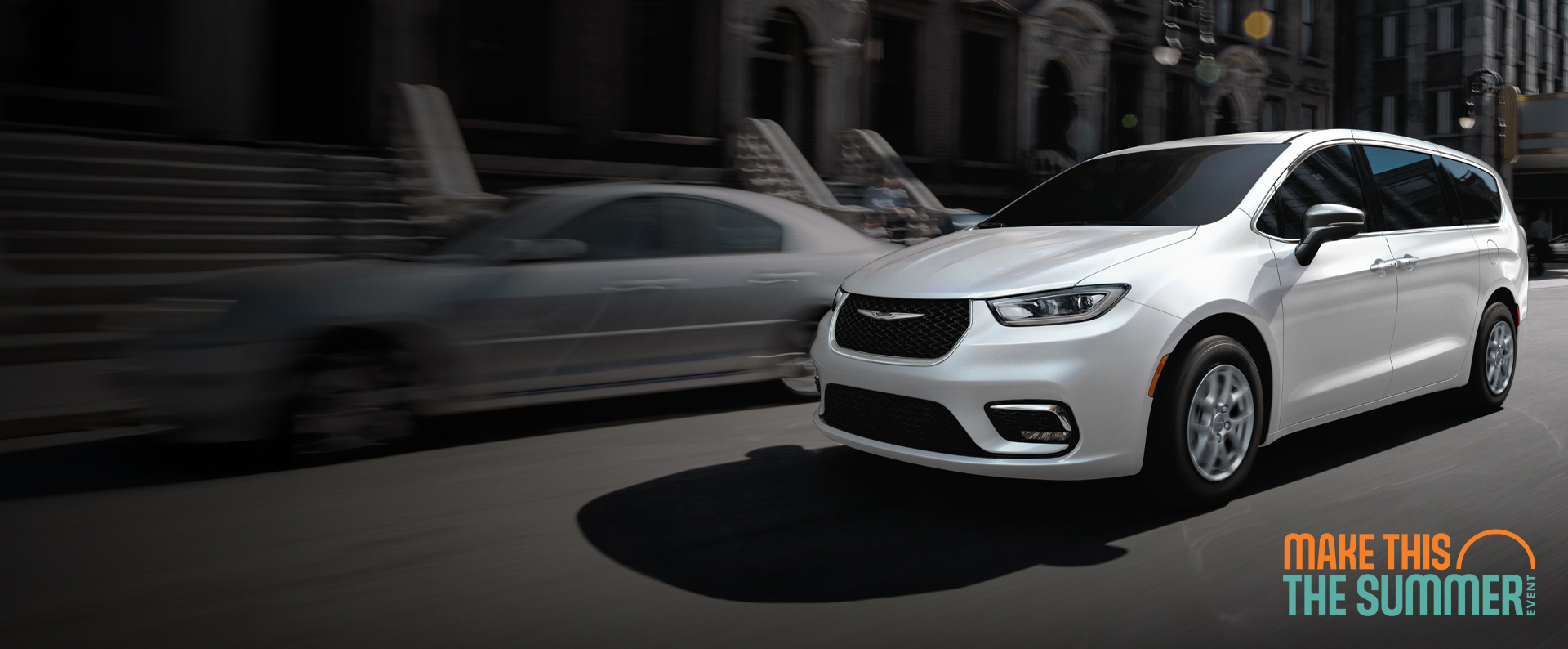 Una Chrysler Pacifica Select 2026 blanca circulando por la calle de una ciudad. Conviértelo en el evento del verano.
