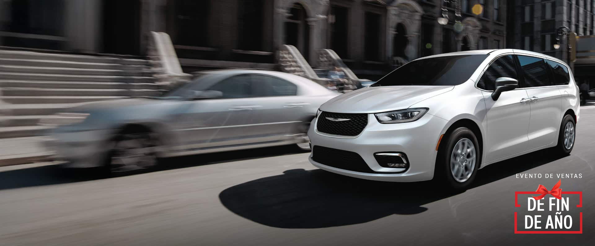 Una Chrysler Pacifica Select 2026 blanca circulando por la calle de una ciudad. Evento de ventas Fin de año.