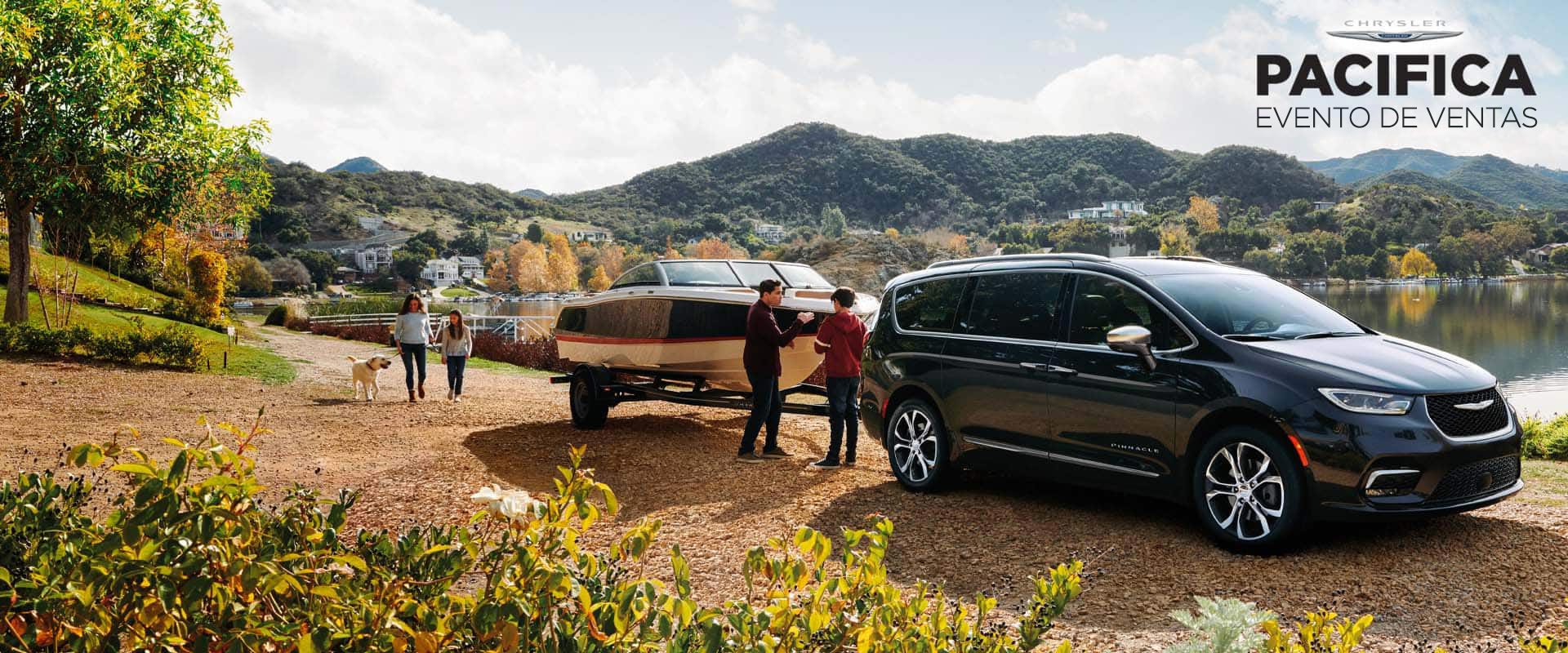 Perfil desde el ángulo del lado del pasajero de un modelo a gasolina de Chrysler Pacifica Pinnacle 2024 negra estacionada junto a un lago, remolcando una lancha y con una familia de cuatro personas y su perro cerca. Evento de ventas para Pacifica.