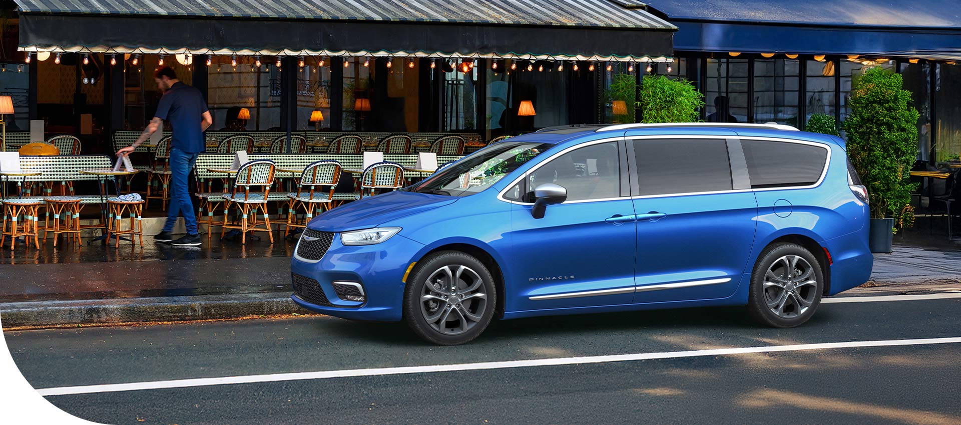 Una Chrysler Pacifica Limited 2026 azul estacionada en frente de un restaurante.