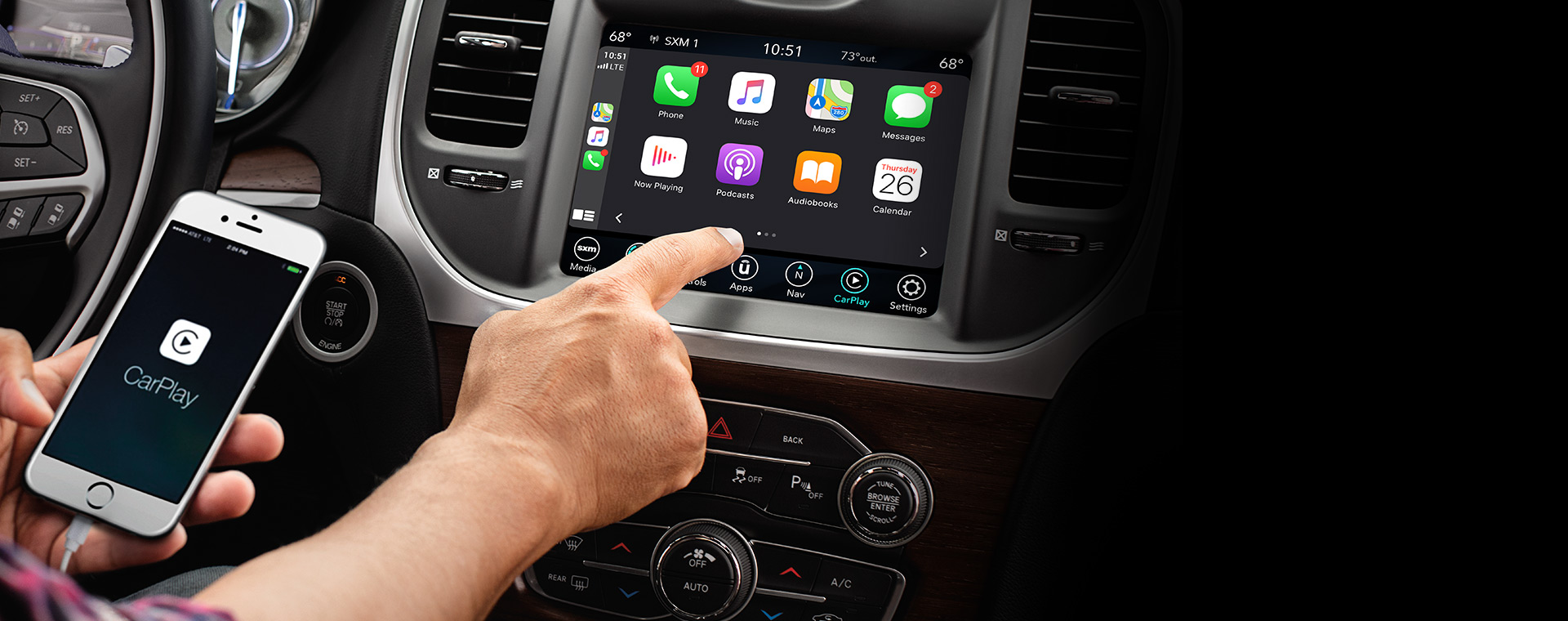 El conductor en una Chrysler Pacifica Limited 2021 utilizando la pantalla táctil Uconnect para acceder a las características de su smartphone.