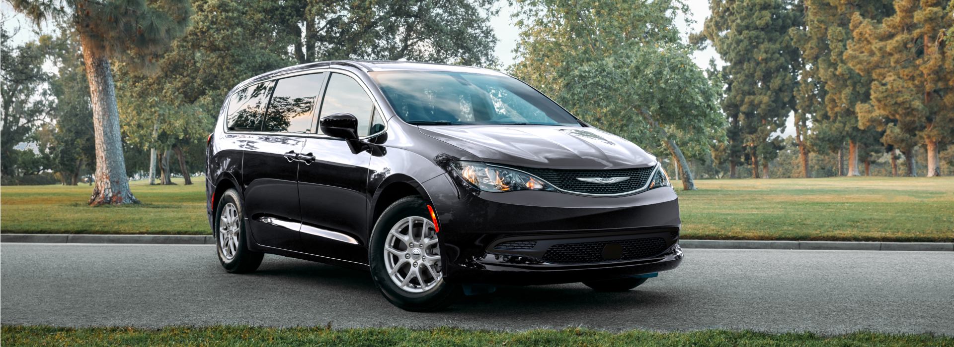 Un ángulo frontal del lado del pasajero de una Chrysler Voyager 2026 en un parque.